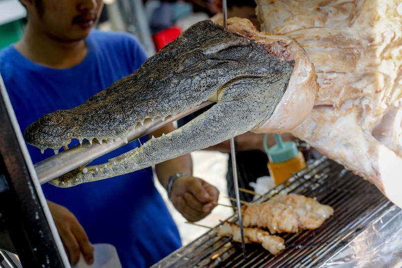 泰國豬價自去（2021）年中開始狂飆，泰國民眾開始改用其他食材替代，也令「鱷魚肉」需求開始成長。圖為泰國鱷魚肉串攤販。（歐新社）