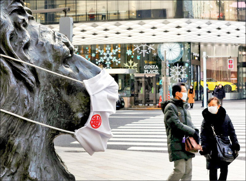 日本26日通報確診數破7萬，圖為東京街頭一尊獅子雕像被戴上口罩。（路透）