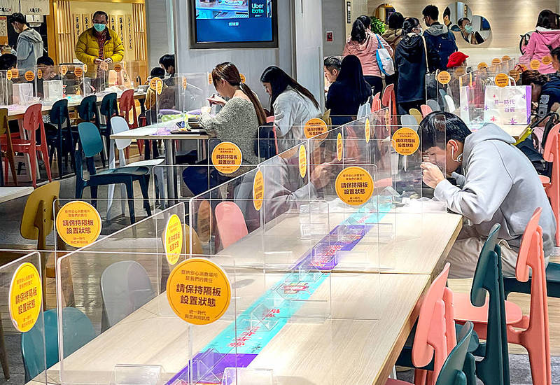 People eat separated by screens at a food court in Taipei on Monday.
Photo: CNA