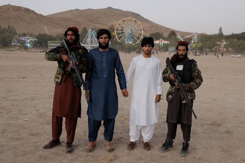 两名造访游乐园的游客与手持枪枝的神学士士兵们合照，他们身后就是喀布尔规模最大的游乐园。（路透）(photo:LTN)