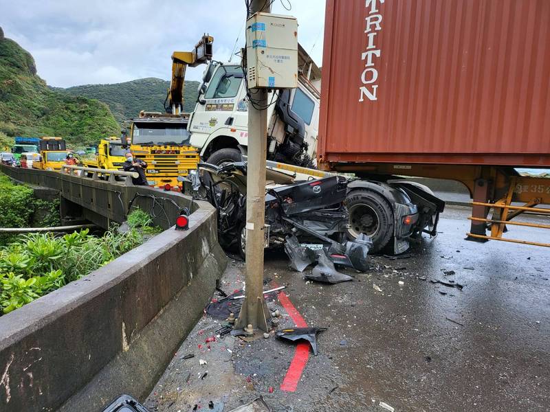 轎車夾在貨櫃車及水泥護欄中間，駕駛受困車內。（記者吳昇儒翻攝）