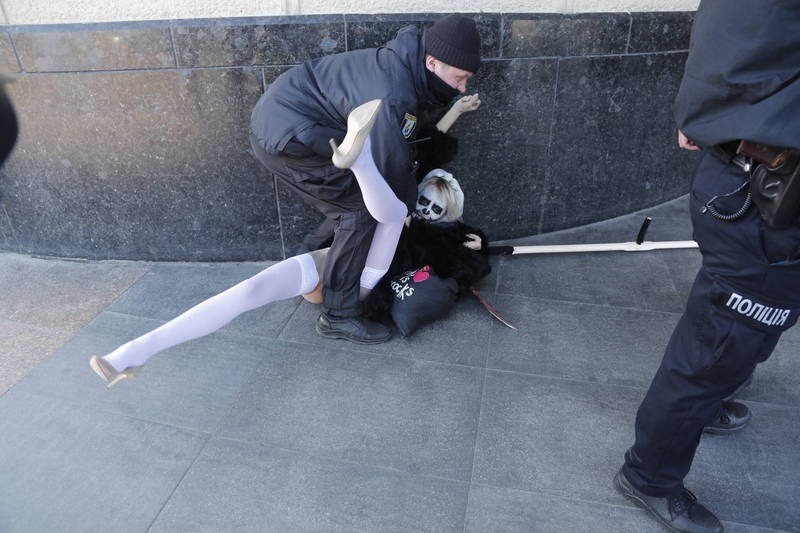 女子疑触犯妨碍风化或公然猥亵等罪，随后被警方拘捕，并被裹上黑色大衣。（欧新社）(photo:LTN)