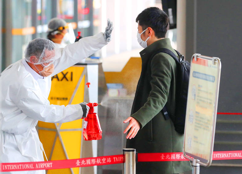 A health worker sprays disinfectant on an arriving passenger at Taipei International Airport （Songshan airport） yesterday.
Photo: CNA