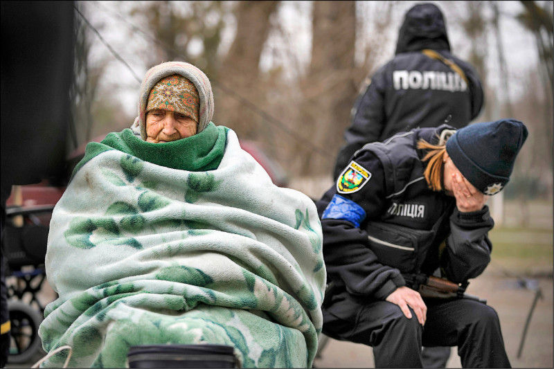 烏克蘭伊爾平一名9旬老婦裹著厚厚毛毯撤離家園，一旁的員警不忍落淚。（美聯社）