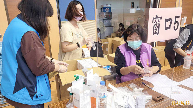 Civil servants at a Keelung government office yesterday prepare rapid COVID-19 test kits for distribution.
Photo: Lu Hsien-hsiu, Taipei Times