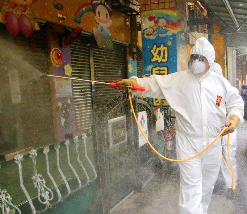 
A Kaohsiung City Government employee sanitizes the outside of a kindergarten in Kaohsiung’s Fongshan District yesterday.
Photo: CNA