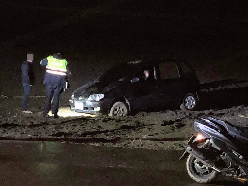 余男帶女友到觀音海水浴場看海，車子卻受困沙灘動彈不得，警方獲報前往協助並連繫拖吊業者，耗費一番工夫終於將車子拖離沙灘。（記者鄭淑婷翻攝）