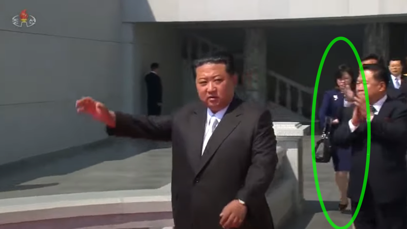 北韓領導人金正恩15日在平壤出席閱兵活動，身邊出現一名身著套裝，作秘書打扮的神秘女子（綠圈）。（翻攝朝鮮中央電視台，本報後製）