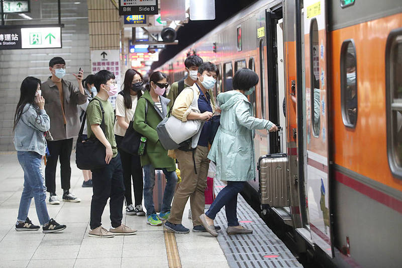 
Riders line up to get on a Taiwan Railways Administration train in Taipei yesterday.
Photo: CNA