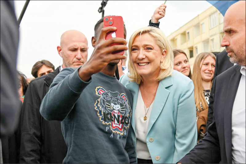 右翼民粹主義政黨「國民聯盟」候選人瑪琳．勒班二十二日在法國北部海岸城市貝爾克與支持者自拍。（法新社）