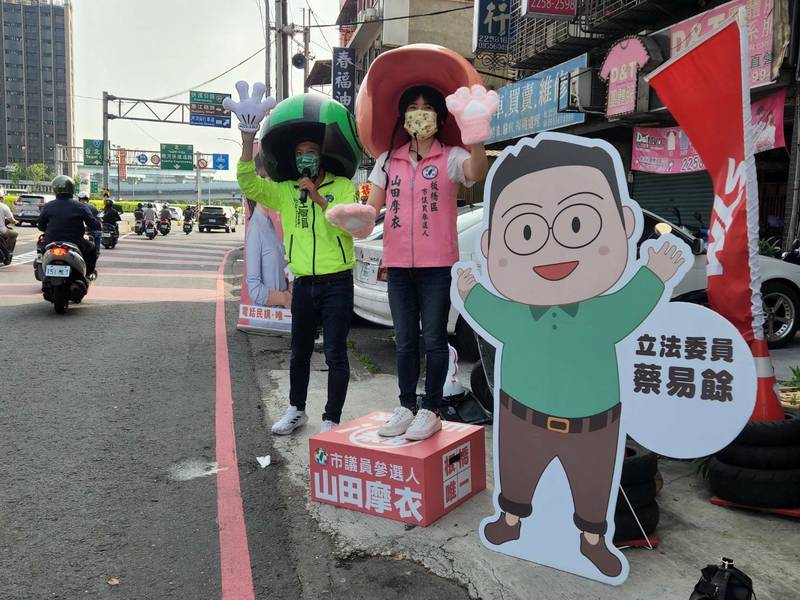 民進黨新北市板橋區議員參選人山田摩衣（右）今天邀請台南市大新營區議員參選人王宣貿站台，還有立委蔡易餘的人形看板陪同拜票。（山田摩衣提供）