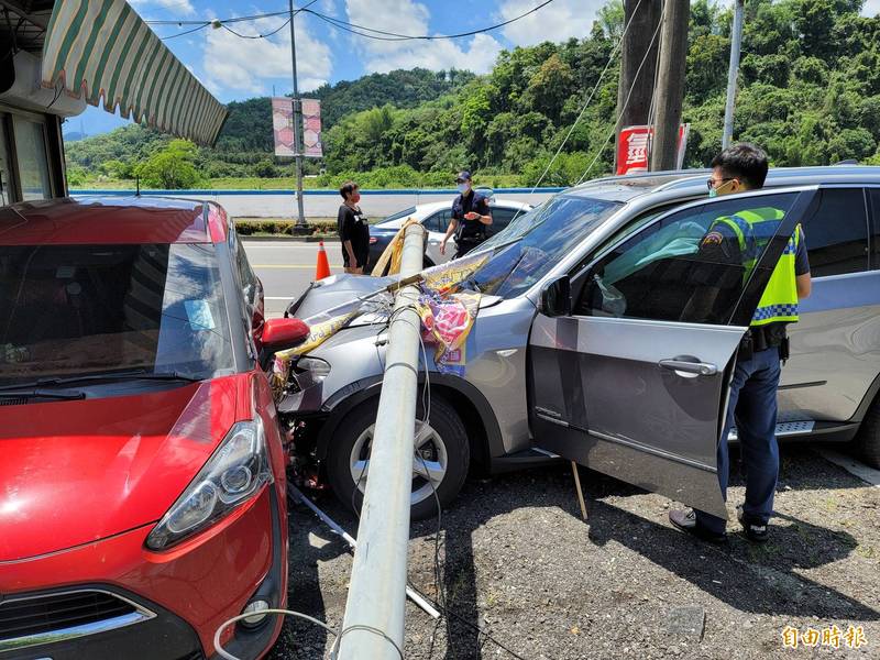 BMWX5休旅車撞飛路邊路燈桿，橫躺在引擎蓋上。（記者佟振國攝）