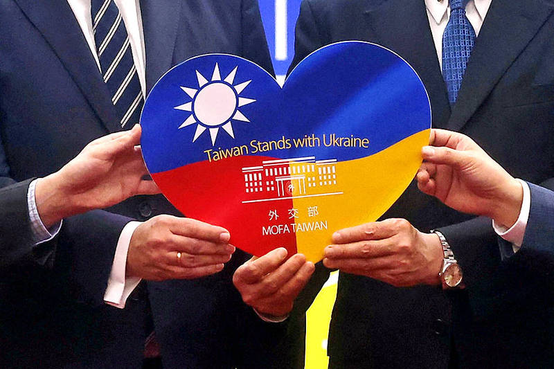 
Minister of Foreign Affairs Joseph Wu and Polish Office in Taipei Director Cyryl Kozaczewski display support for Ukraine following a news conference in Taipei on March 7 announcing humanitarian aid for Ukrainians.
Photo: Ann Wang, Reuters