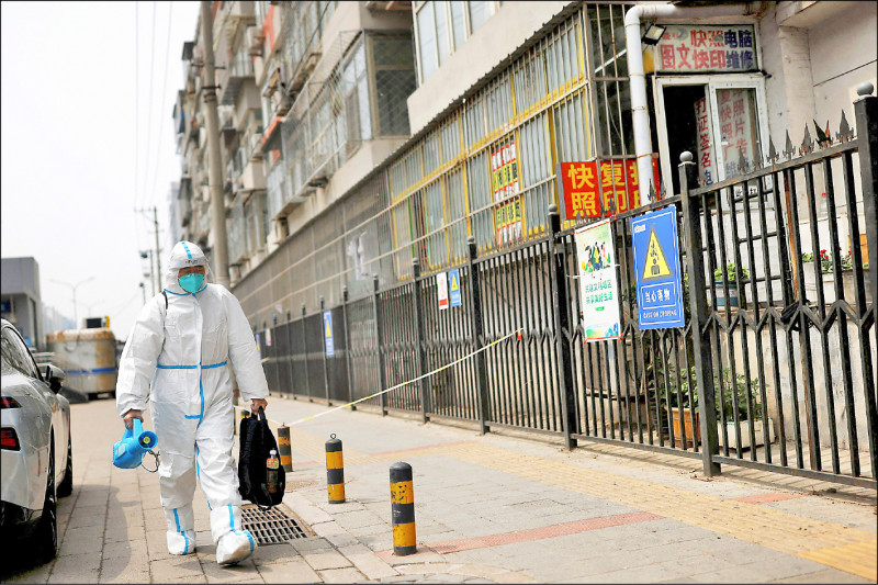 北京病例持續增加，五一連假期間 ，全市餐飲單位暫停內用，當地加緊蓋大型方艙，其中可收容一千兩百人的小湯方艙醫院已於一日啟用。圖為穿防護裝備的工作人員在封鎖區域走動清消。(路透)