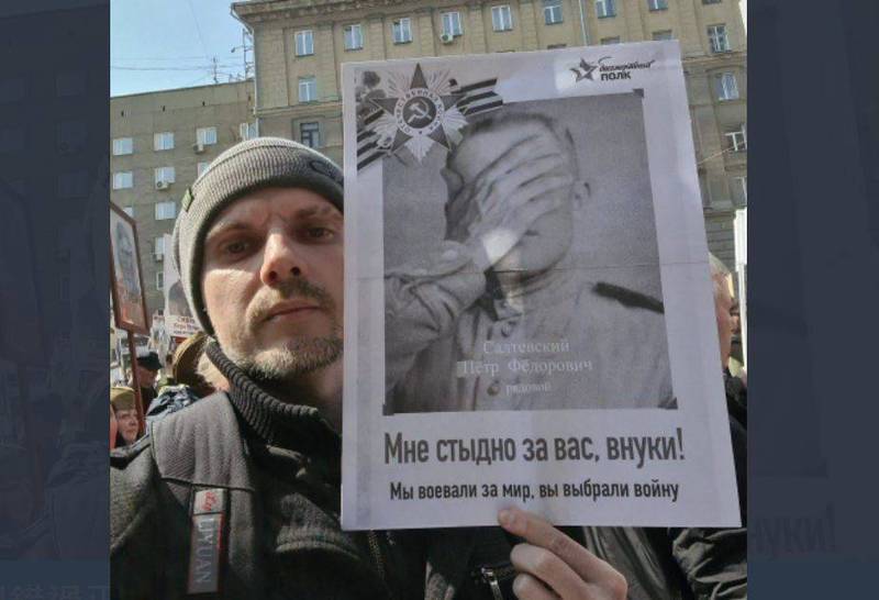 俄羅斯今在莫斯科紅場舉行「勝利日」閱兵，一名在新西伯利亞市參與勝利日「不朽軍團」遊行的男子則高舉抗議海報。（圖取自推特）