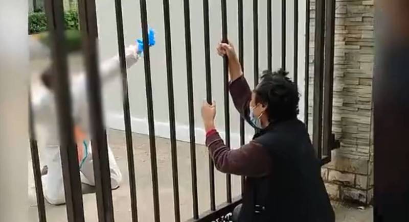 上海奶奶在社區鐵柵欄前請求防疫人員讓她外出看病。（圖擷取自微博）