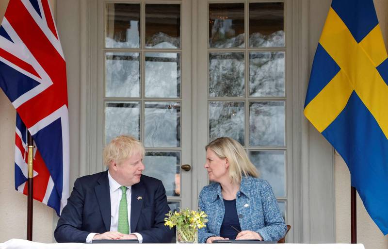 英國首相強森（左）與瑞典總理安德森（右）在簽署文件時交談。（法新社）