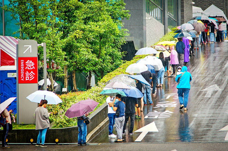 
People line up in the rain for COVID-19 testing in New Taipei City’s Tucheng District yesterday.
Photo: CNA