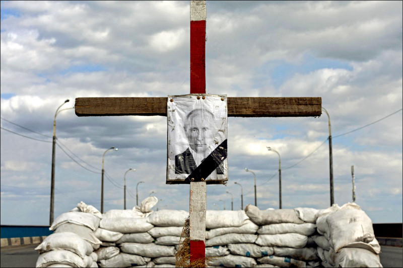 烏克蘭中部城市第聶伯羅外的檢查哨10日豎起一座十字架，並掛上俄羅斯總統普廷的肖像，暗諷此處為普廷之墓。（路透）