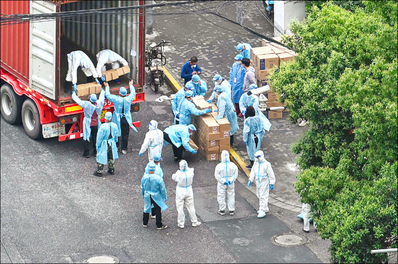 上海静安区一处防疫封锁区十三日一批穿着防护装的人员从卡车上卸下一箱箱纸箱。（法新社）(photo:LTN)