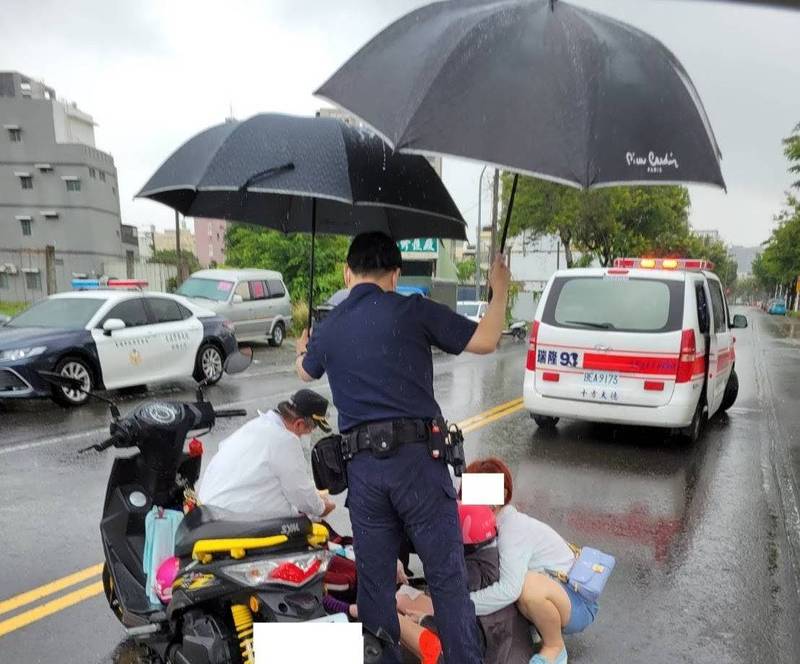 高雄捷警巡邏發現交通事故，幫忙傷者撐傘等待救援。（記者王榮祥翻攝）