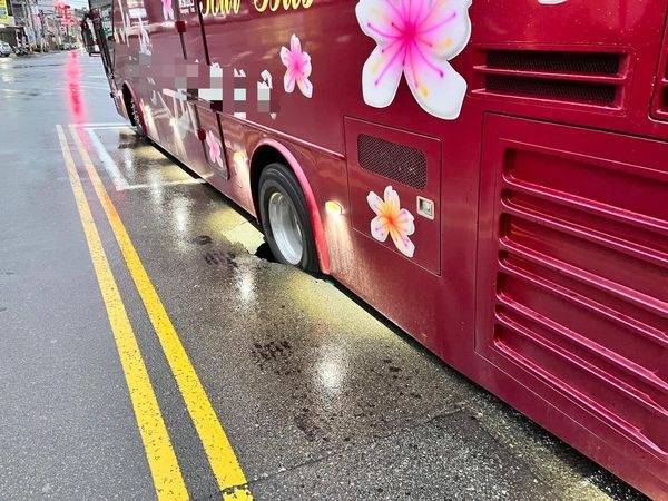 苗栗市至公路接近國華路口處，因連續雨勢致路面塌陷，路經的遊覽車輪胎陷入，動彈不得。（苗栗警分局提供）