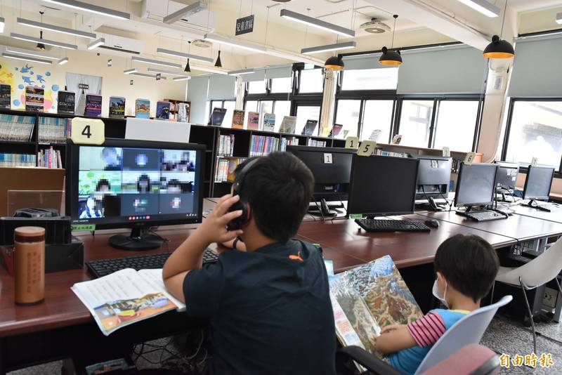 一名國小男童帶著讀幼兒園弟弟到土庫鎮圖書館借用電腦線上上課，哥哥上課時弟弟安靜坐在一旁看書。（記者黃淑莉攝）