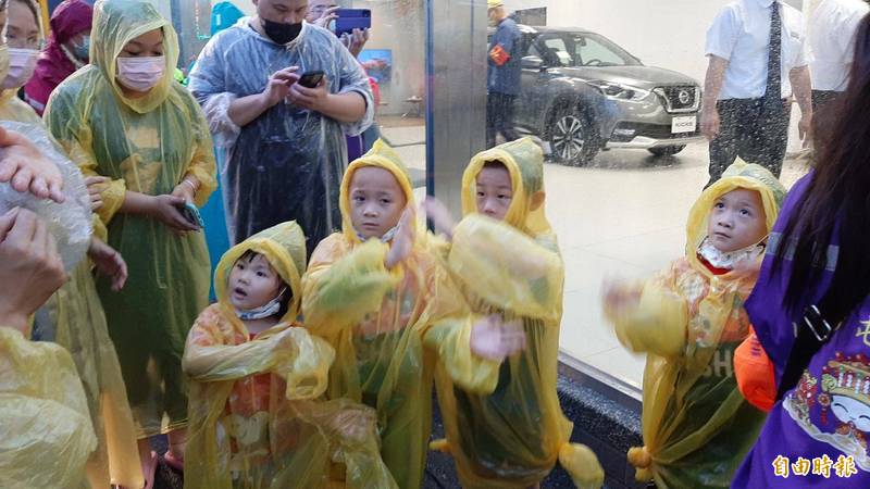 4名幼童穿雨衣唱歌給白沙屯媽祖聽。（記者張軒哲攝）