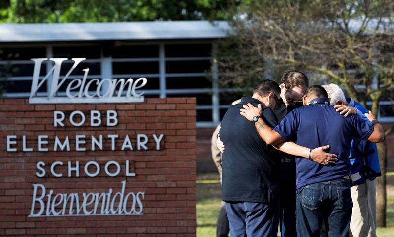 美國德州尤瓦爾迪洛伯小學（Robb Elementary School）24日驚傳一名18歲槍手闖入，造成21名師生遇害。一群人25日在校門前相擁默哀。（路透）