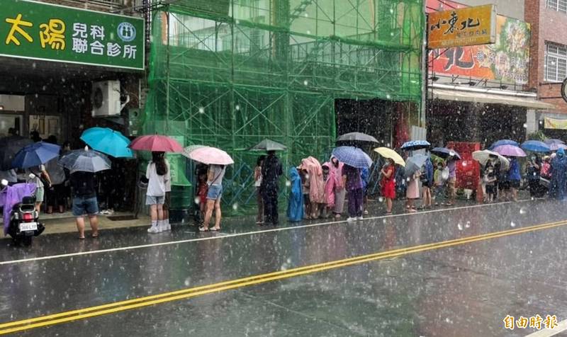 家長帶著小孩冒著大雨在馬路排隊等待打疫苗，相當的辛苦。（記者葉永騫攝）