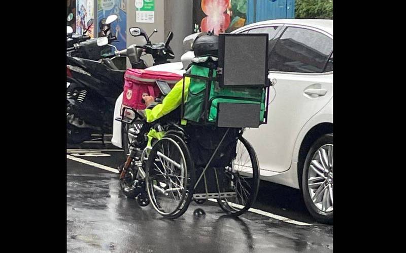 有網友在台北市信義區目擊一名坐著輪椅外送的外送員冒雨跑單送餐，照片PO出後感動許多網友。（圖取自臉書社團「信義區三兩事」）