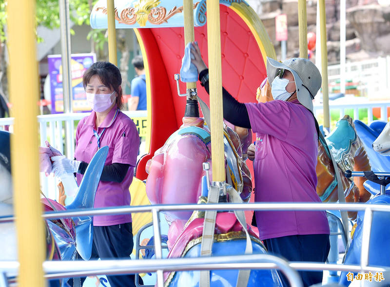 Workers yesterday disinfect a merry-go-round at the Taipei Children’s Amusement Park to curb the spread of COVID-19.
Photo: Peter Lo, Taipei Times