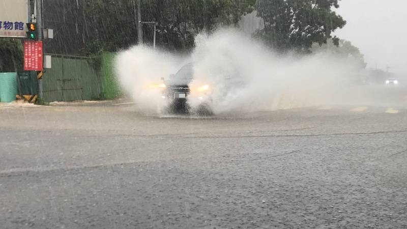 大雨狂炸三義木雕街，馬路成為河流，行經的汽車「乘風破浪」激起巨大水花。 （民眾提供）