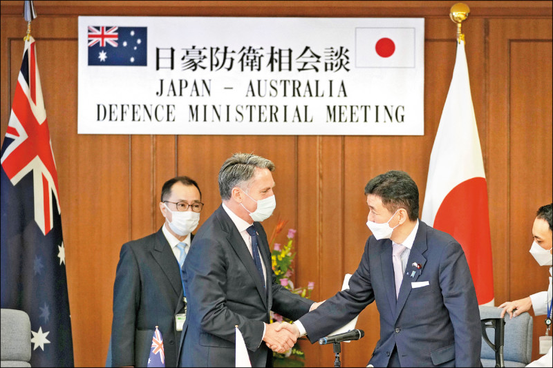 澳洲副總理兼國防部長馬勒斯（左）與日本防衛大臣岸信夫十五日在東京的聯合記者會結束後握手。（美聯社）