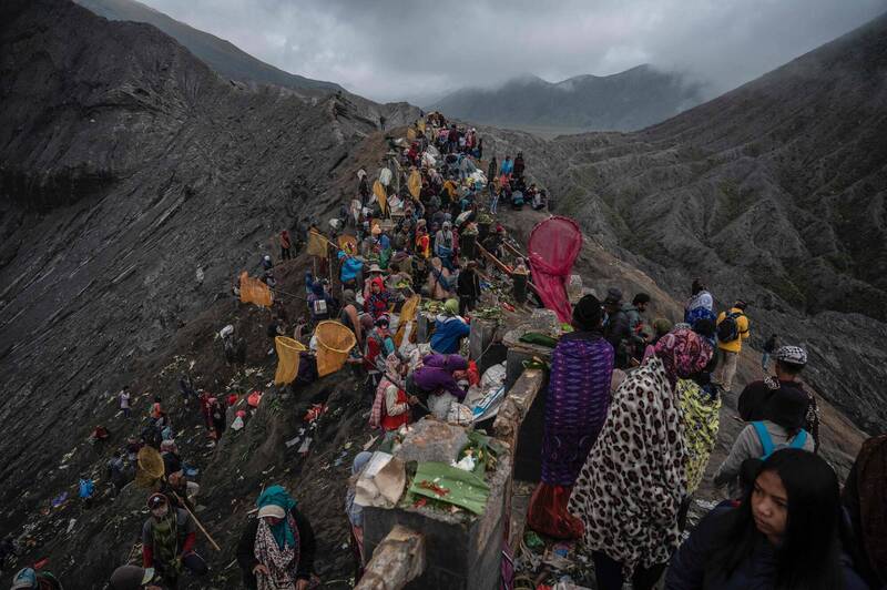 騰格爾族人16日爬上印尼一座活火山，進行傳承數百年的宗教儀式「亞德尼雅．卡沙達節」，參加者將農作物和活牲投入悶燒的活火山口中。（法新社）