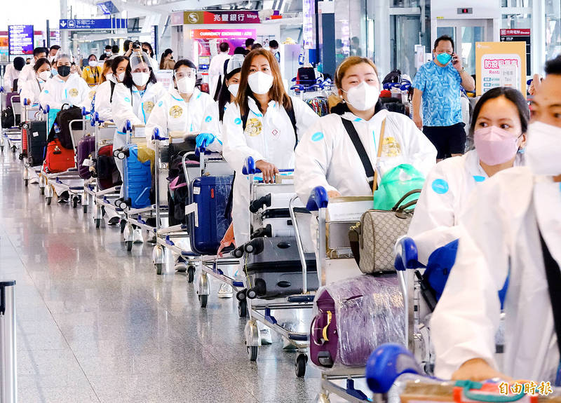 People wearing an assortment of personal protective equipment line up at Taiwan Taoyuan International Airport yesterday.
Photo: Chu Pei-hsiung, Taipei Times