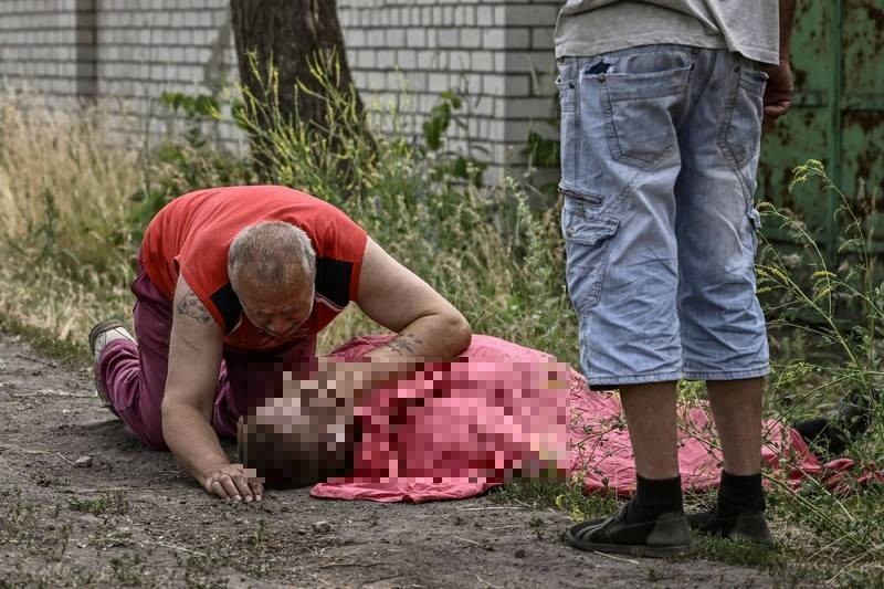 利西昌斯克一名市民不幸受战火波及丧生，他的父亲在一旁难过的抚摸儿子的脸。（法新社）。(photo:LTN)