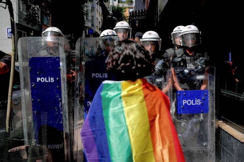 土耳其同志大遊行26日登場，伊斯坦堡的塔克西姆廣場（Taksim Square）周圍地區發生激烈警民衝突，一名身著彩虹旗幟的人勇敢站在警察面前。（法新社）