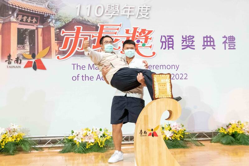 台南市長黃偉哲打破學校頒獎典禮傳統合照模式，被得獎學生「公主抱」，稱讚這位學生硬舉80公斤的他沒問題。（台南市府提供）