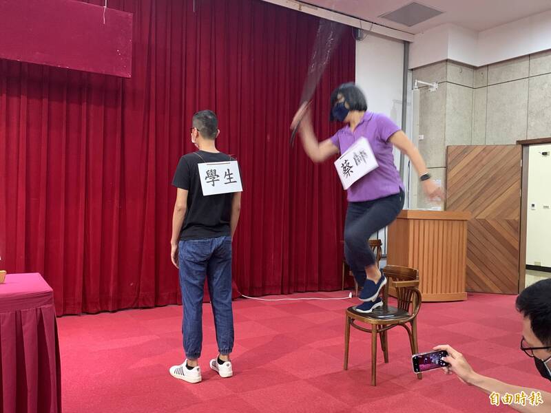 記者會現場模擬體育班導師站在椅子上、手持曲棍球棒「跳殺」學生背部。（記者方志賢攝）