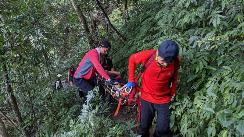 消防人員用擔架將呂男扛下山。（記者張軒哲翻攝）