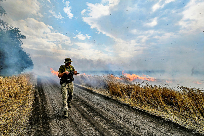 一名乌克兰军人17日在札波罗热和顿内茨克地区交界的前线附近，走过熊熊烈火燃烧的麦田。（路透）(photo:LTN)