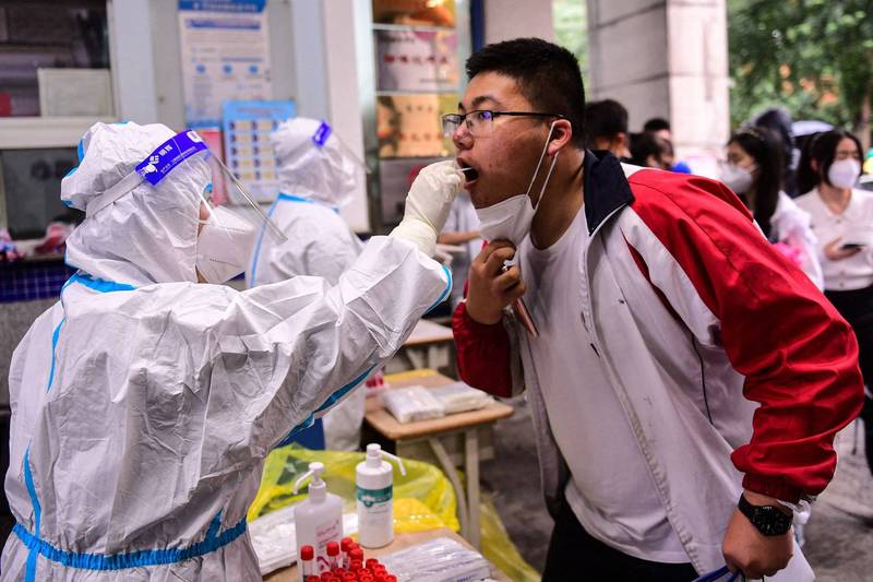 中國瀋陽市近日多個核酸檢測點停止檢測，主因是多名暱稱「大白」的採樣員抗議數月工資拖欠憤而罷工。圖為6月上旬身穿全套防護服的大白在瀋陽為準備參加高考的考生採檢核酸。（法新社資料照）