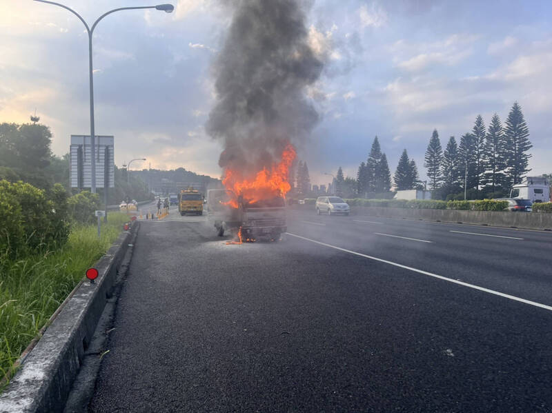 國道3號下安康交流道前今下午驚傳火燒車，一部小貨車開到一半竟突然自燃，消防人員獲報馳援灌救，駕駛座已全遭焚毀。（記者闕敬倫翻攝）