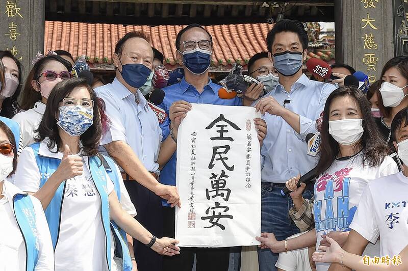 國民黨主席朱立倫（中）陪同台北市長參選人蔣萬安（中右）到龍山寺參拜，龍山寺董事長黃書瑋（中左）送上「全民萬安」字帖給蔣萬安。（記者陳志曲攝）