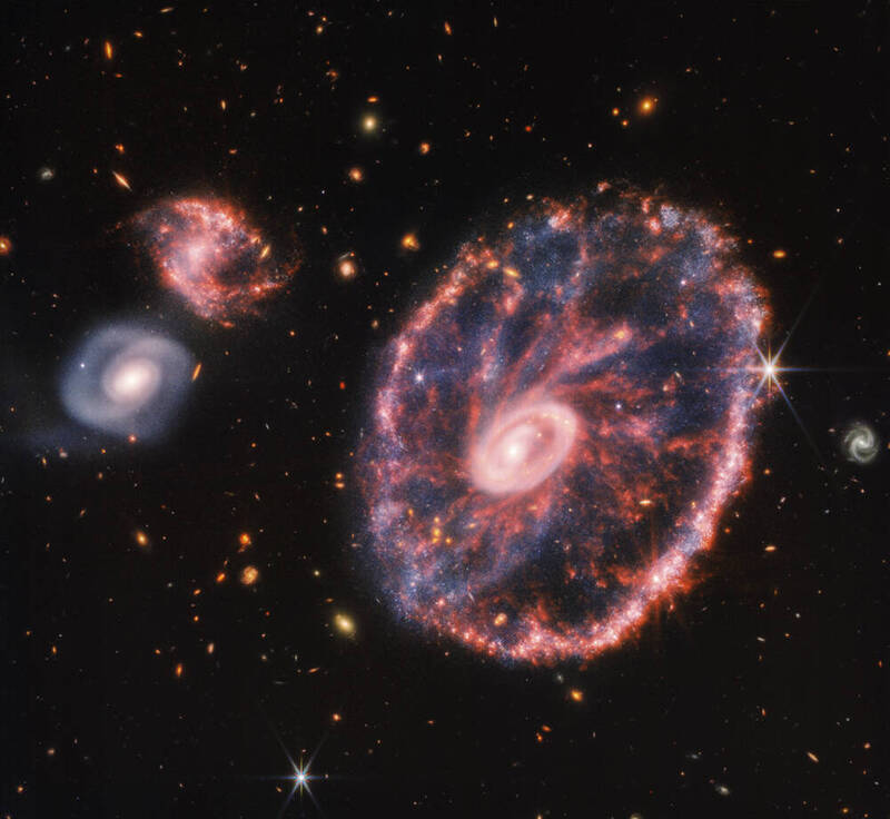 車輪星系（右）的兩個環從碰撞中心向外膨脹，就像石頭被扔進池塘後的漣漪，由於這些獨特的特徵，天文學家稱之為「環狀星系」。（美聯社）