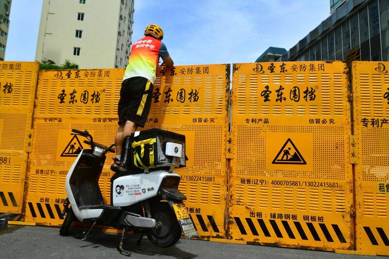 中国海南三亚近来採取严厉疫措施，外送人员仅能站在摩托车上，把物品交给封锁屏障另一端的人员。（路透）(photo:LTN)