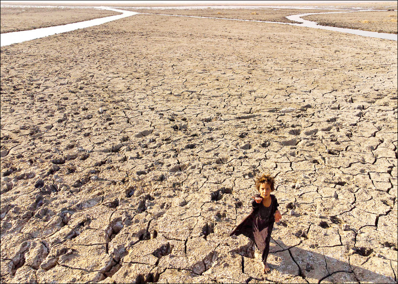 全球多地頻現旱象，伊拉克濟加爾省南部城鎮濕地23日有孩童在乾涸地面行走。（法新社）