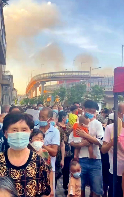 网路流传重庆居民24日顶着酷热高温，大排长龙等做核酸检测。远处为因连日热浪引发的山林大火浓烟。（取自网路）(photo:LTN)