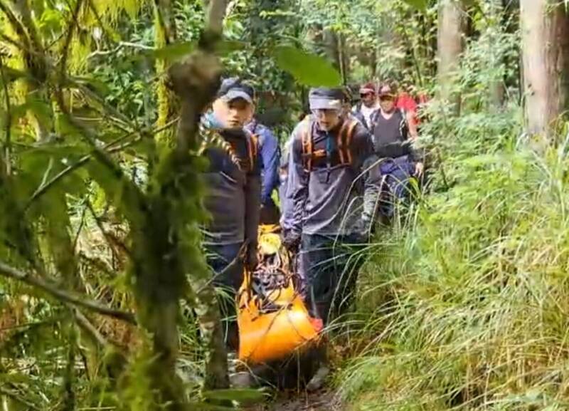 南湖大山發生曾姓女登山客摔傷，搜救人員以接力方式抬下山。（圖由宜縣消防局提供）